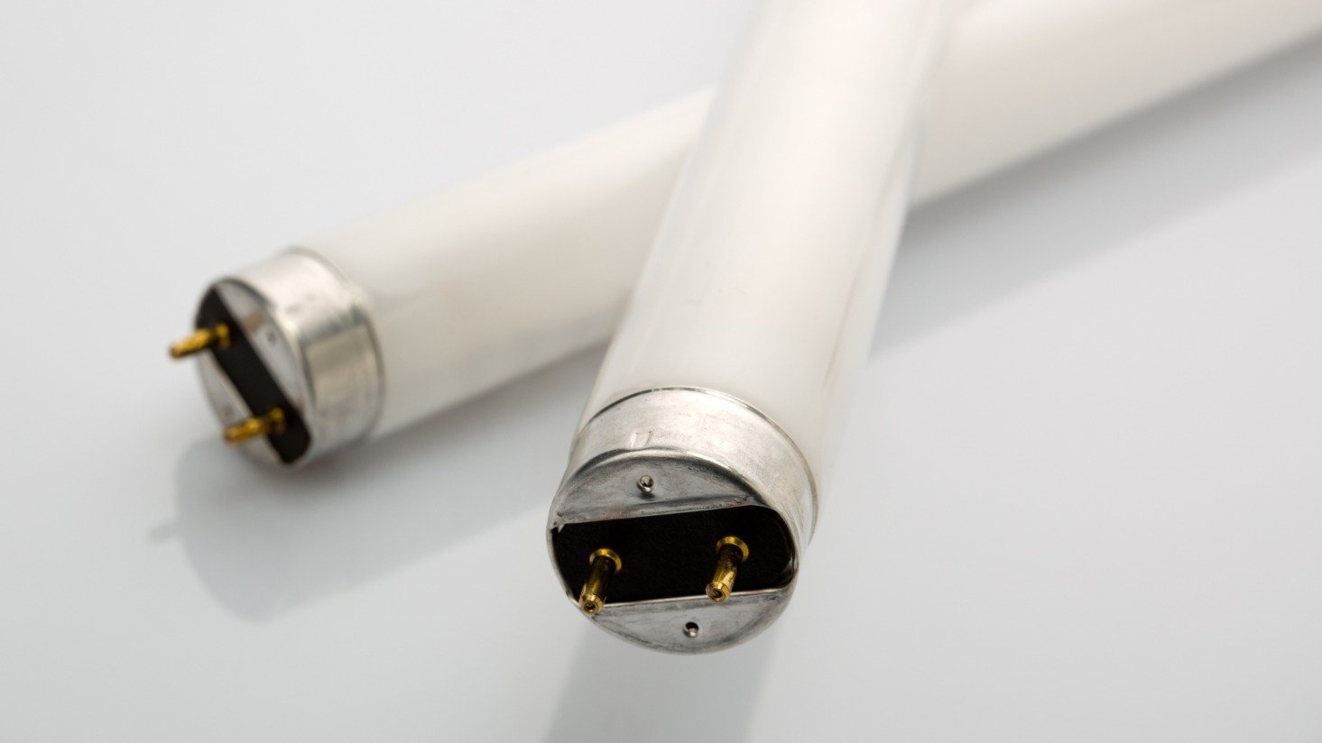 What is a ballast factor and how does it affect fluorescent tubes?